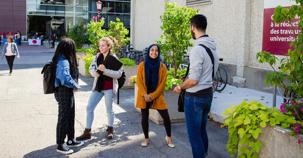 Group of four students having a conversation outdoors on campus